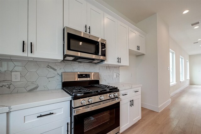 kitchen featuring stainless steel appliances, light stone countertops, white cabinets, and light hardwood / wood-style flooring