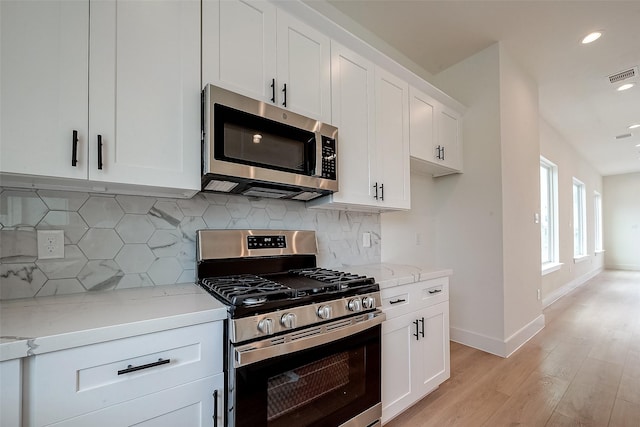 kitchen with white cabinetry, light stone counters, appliances with stainless steel finishes, and decorative backsplash