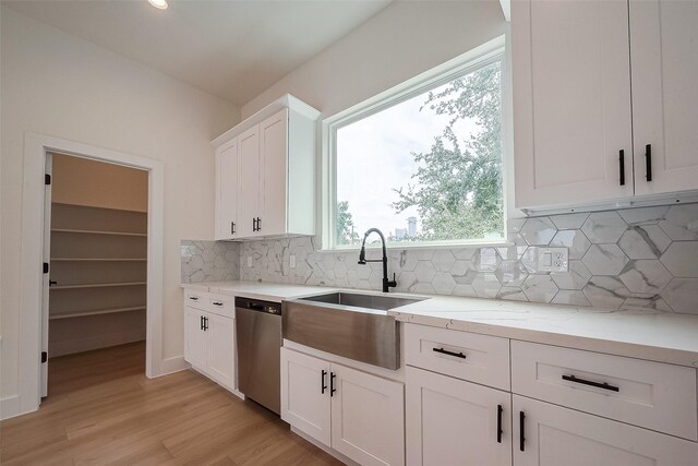 kitchen with light hardwood / wood-style floors, sink, light stone counters, stainless steel dishwasher, and white cabinetry