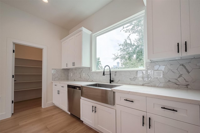 kitchen with light hardwood / wood-style floors, tasteful backsplash, white cabinetry, stainless steel dishwasher, and light stone counters