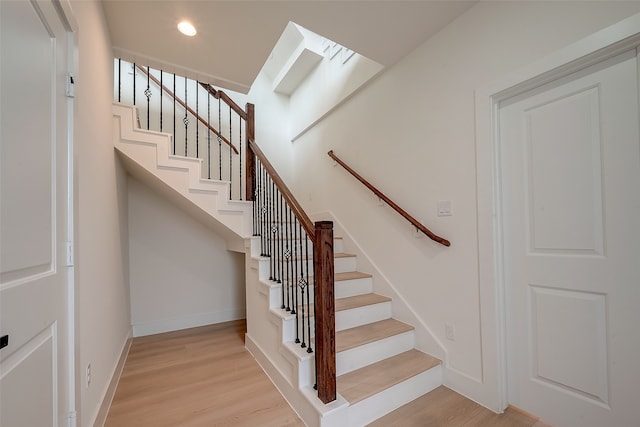 stairway with a skylight and hardwood / wood-style floors