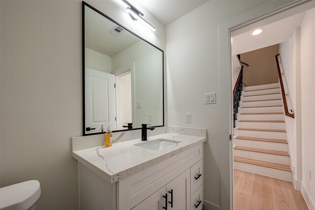 bathroom with hardwood / wood-style flooring, vanity, and toilet