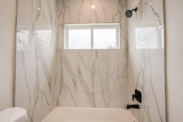 bathroom with tiled shower / bath combo and toilet