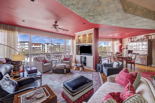 living room with plenty of natural light, ceiling fan with notable chandelier, and hardwood / wood-style flooring