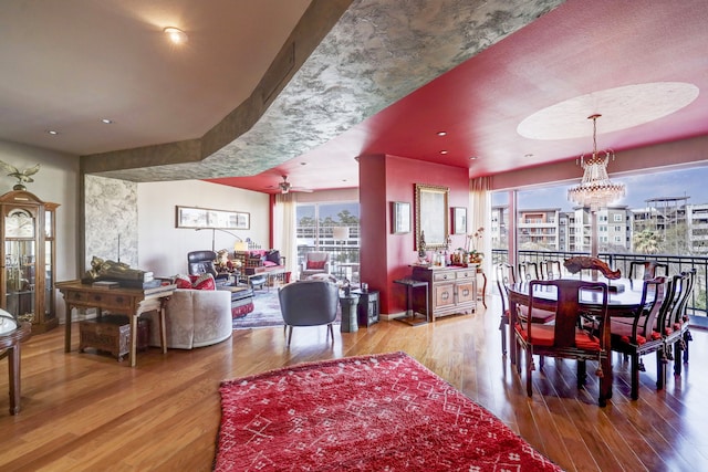 dining space featuring ceiling fan with notable chandelier and wood-type flooring