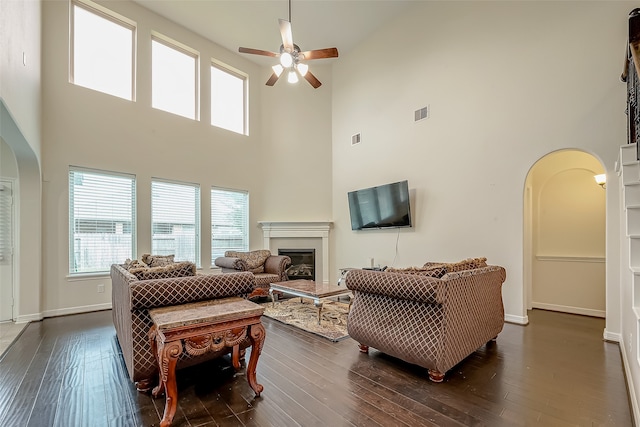 living room featuring ceiling fan, a towering ceiling, and dark hardwood / wood-style flooring