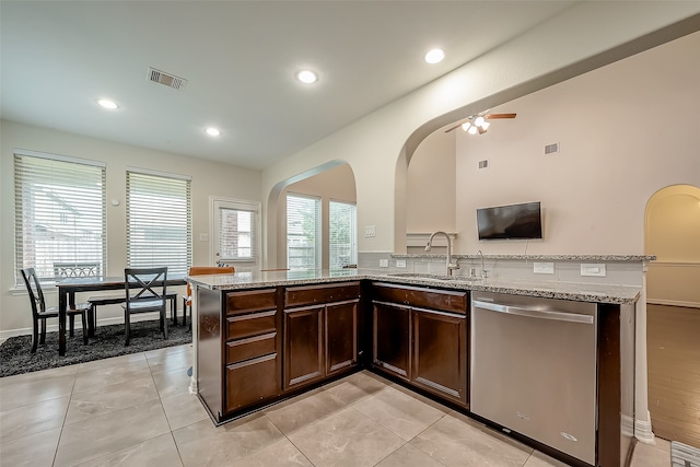 kitchen with dark brown cabinets, light stone counters, sink, ceiling fan, and stainless steel dishwasher