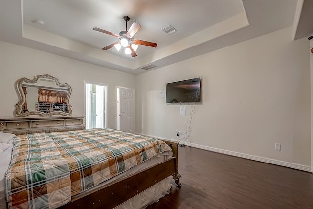 bedroom with a tray ceiling, dark hardwood / wood-style floors, and ceiling fan