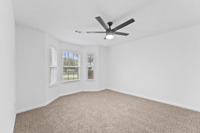 carpeted empty room featuring visible vents, ceiling fan, and baseboards