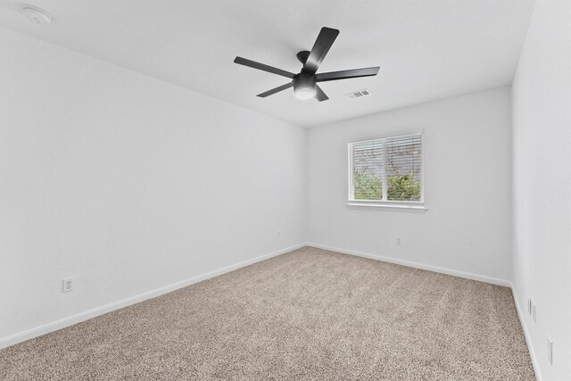 empty room with baseboards, carpet floors, visible vents, and a ceiling fan