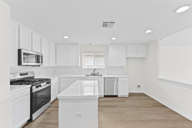 kitchen with stainless steel appliances, white cabinetry, and sink