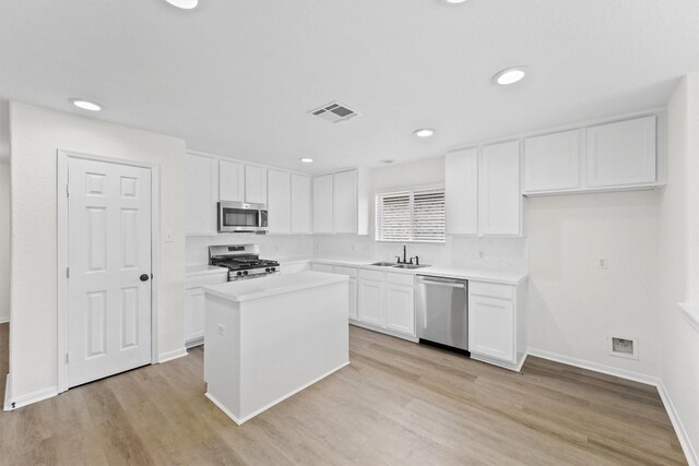 kitchen featuring light wood-type flooring, sink, a center island, appliances with stainless steel finishes, and white cabinets