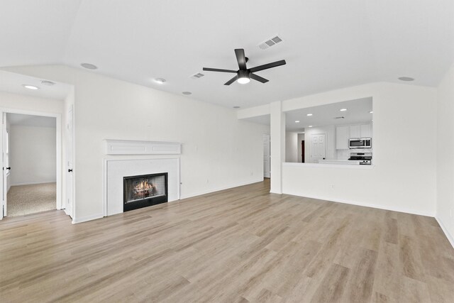 unfurnished living room with light wood-style flooring, visible vents, and a lit fireplace