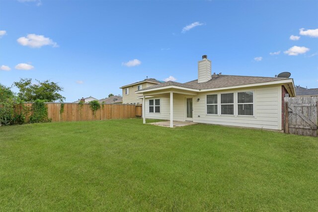 back of property with a fenced backyard, a lawn, a chimney, and a patio