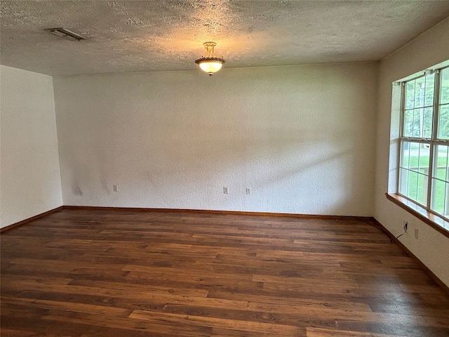 unfurnished room with dark wood-type flooring, a textured ceiling, and a healthy amount of sunlight