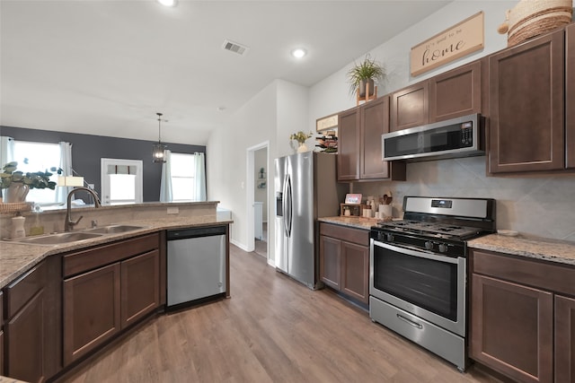 kitchen featuring light wood-type flooring, appliances with stainless steel finishes, sink, and dark brown cabinetry