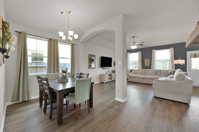 dining space featuring ceiling fan with notable chandelier and dark wood-type flooring