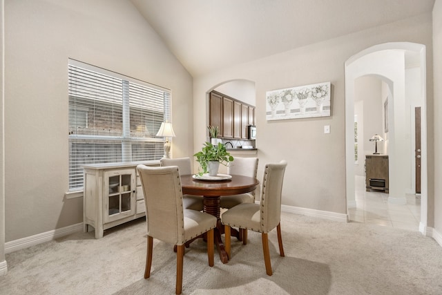 dining room featuring vaulted ceiling and light colored carpet