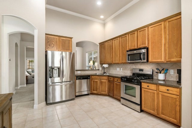 kitchen featuring sink, appliances with stainless steel finishes, ornamental molding, and decorative backsplash