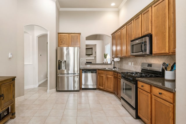 kitchen with stainless steel appliances, dark stone countertops, light tile patterned floors, and sink