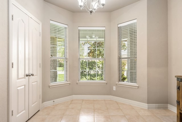 spare room with an inviting chandelier, plenty of natural light, and light tile patterned flooring