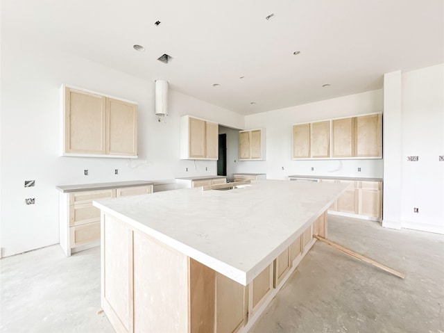 kitchen with light brown cabinetry, a center island with sink, and a breakfast bar