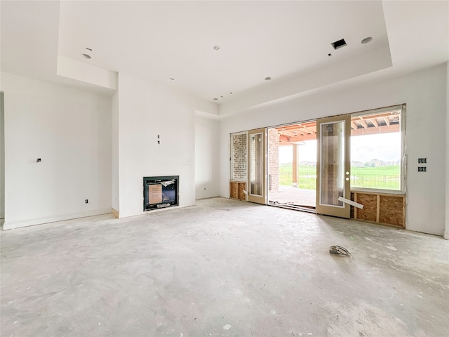 unfurnished living room with concrete floors and a tray ceiling