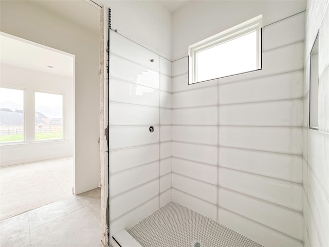 bathroom with a tile shower and tile patterned flooring