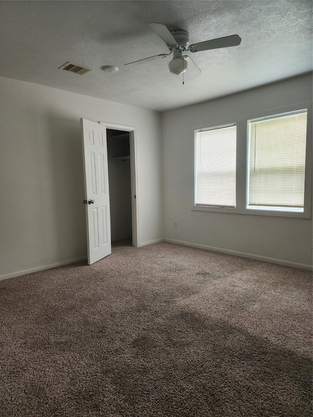 unfurnished bedroom featuring ceiling fan, carpet, and a textured ceiling