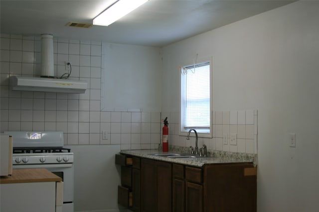 kitchen with butcher block countertops, backsplash, sink, and white range with gas cooktop