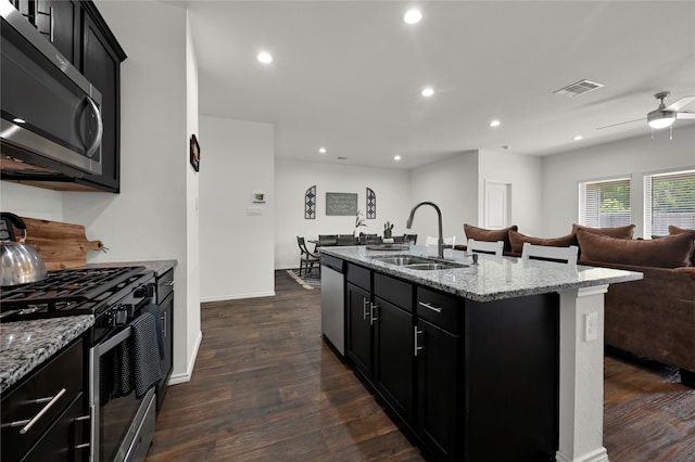 kitchen featuring stainless steel appliances, sink, dark hardwood / wood-style floors, ceiling fan, and a center island with sink