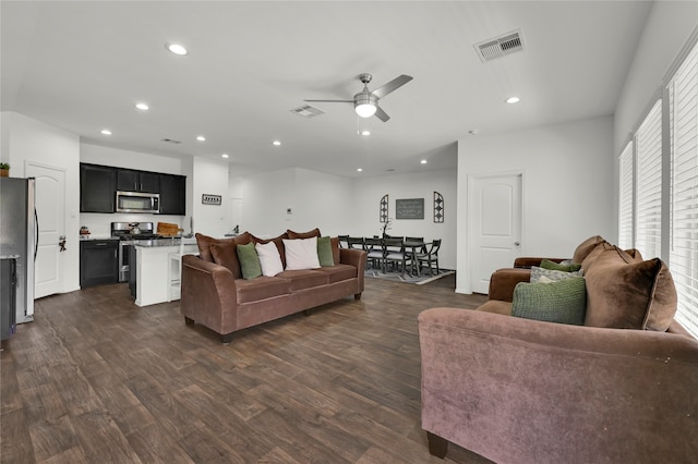 living room featuring dark wood-type flooring and ceiling fan