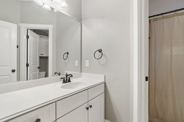 bathroom with walk in shower, vanity, and toilet