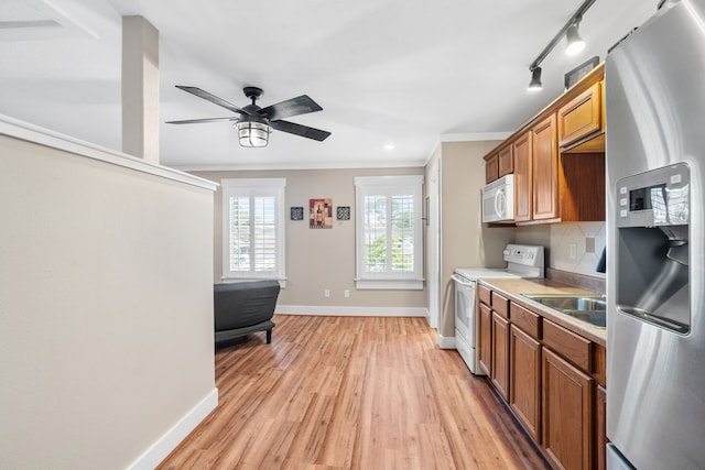 kitchen featuring white appliances, sink, crown molding, ceiling fan, and light wood-type flooring