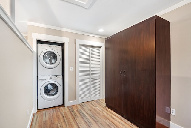 clothes washing area with stacked washing maching and dryer and light wood-type flooring