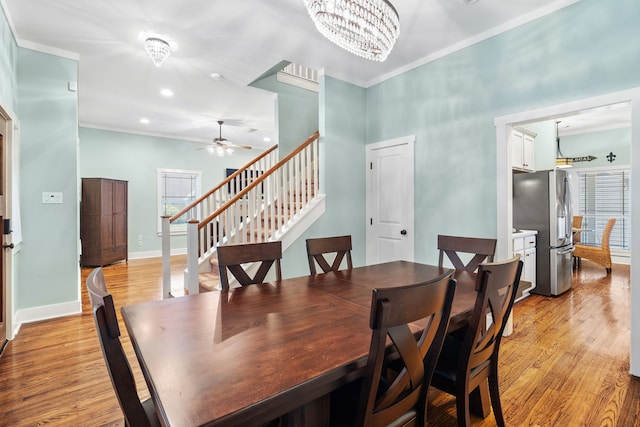 dining room featuring ceiling fan with notable chandelier, light wood-type flooring, ornamental molding, and a wealth of natural light