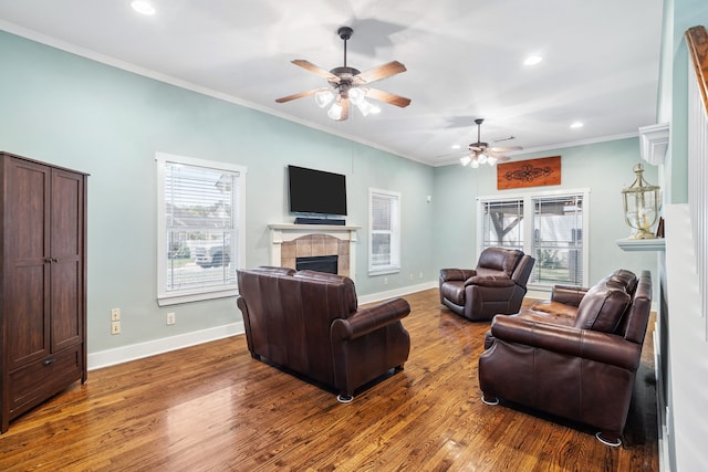 living room with ceiling fan, a fireplace, wood-type flooring, and ornamental molding