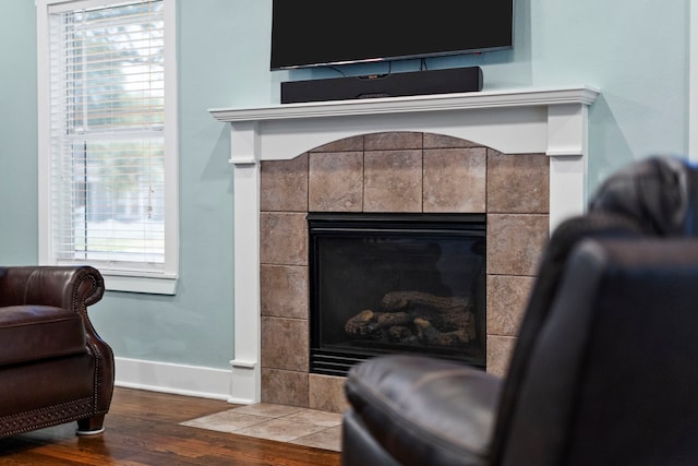 interior details featuring a tile fireplace and wood-type flooring