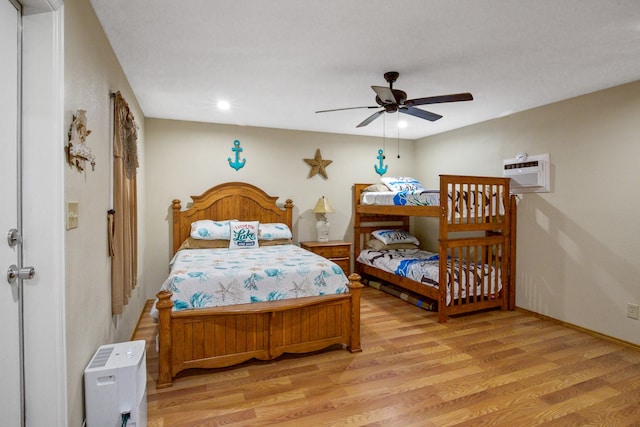 bedroom with an AC wall unit, ceiling fan, and light hardwood / wood-style floors