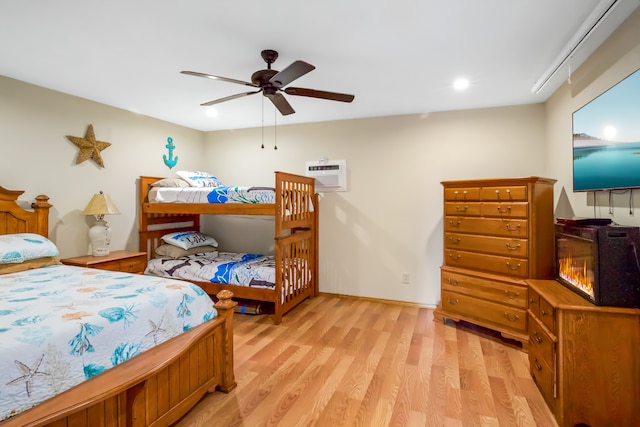 bedroom featuring a wall mounted AC, ceiling fan, and light hardwood / wood-style floors