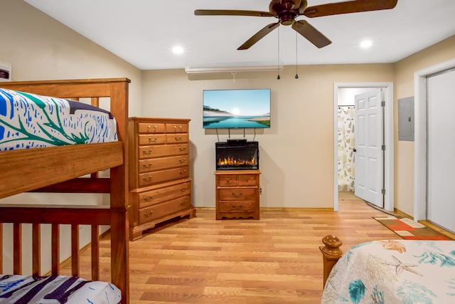 bedroom featuring electric panel, connected bathroom, light wood-type flooring, and ceiling fan