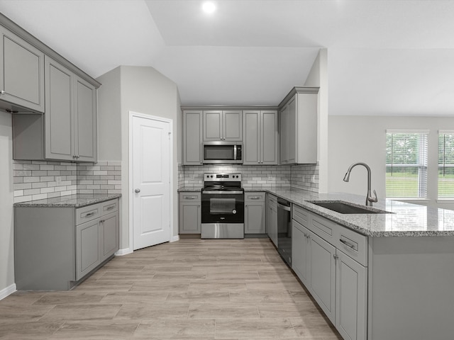 kitchen featuring gray cabinetry, stone countertops, stainless steel appliances, sink, and kitchen peninsula