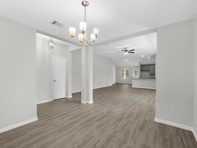 unfurnished living room featuring ceiling fan with notable chandelier and wood-type flooring