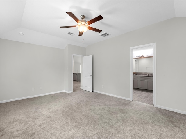 unfurnished bedroom with light colored carpet, ceiling fan, ensuite bath, and vaulted ceiling