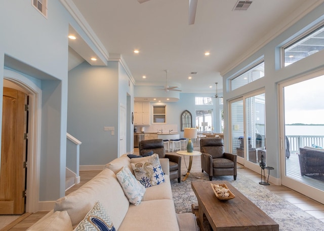 living room with ceiling fan, light wood-type flooring, and crown molding