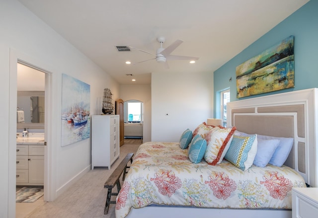 carpeted bedroom with ensuite bath and ceiling fan