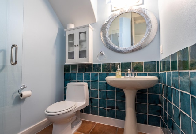 bathroom featuring tile patterned flooring, toilet, and tile walls