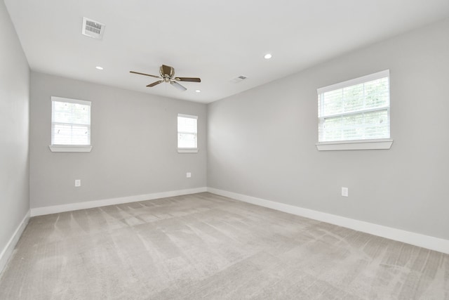 empty room with plenty of natural light, ceiling fan, and light carpet