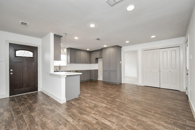 kitchen with gray cabinets, dark hardwood / wood-style floors, kitchen peninsula, and hanging light fixtures