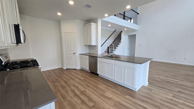 kitchen with white cabinets, sink, light wood-type flooring, appliances with stainless steel finishes, and kitchen peninsula